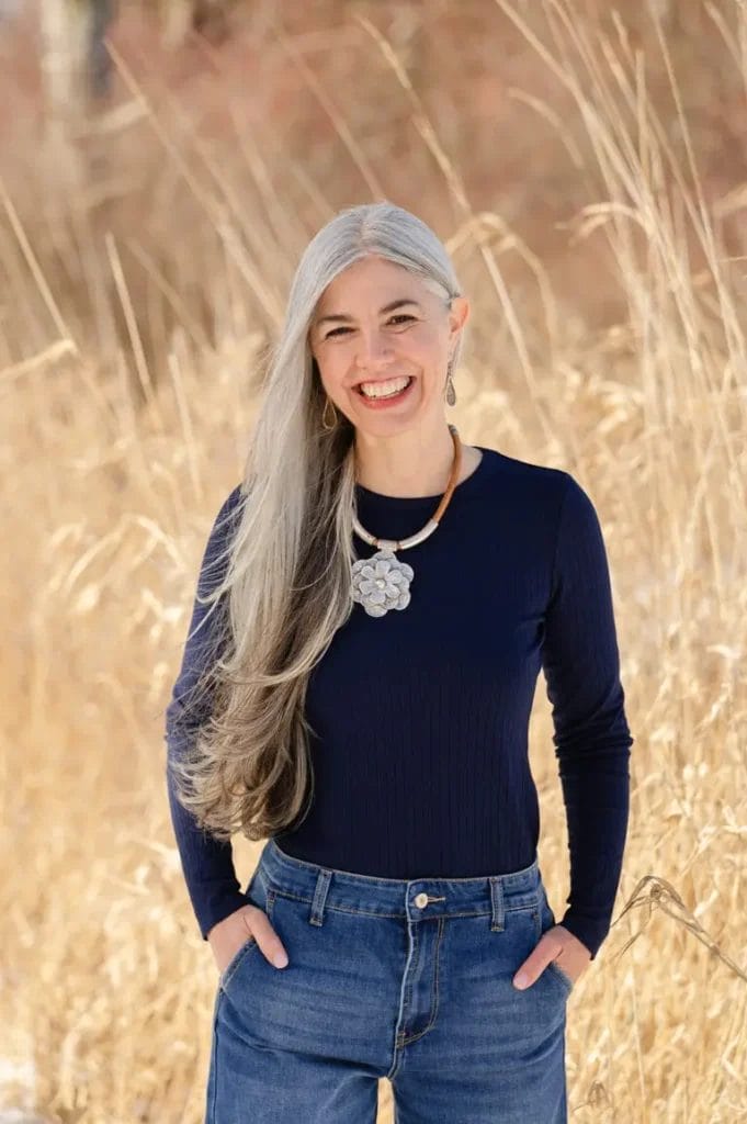 Photo of Emily in a wheat field standing facing the camera with her hands in her pockets.
